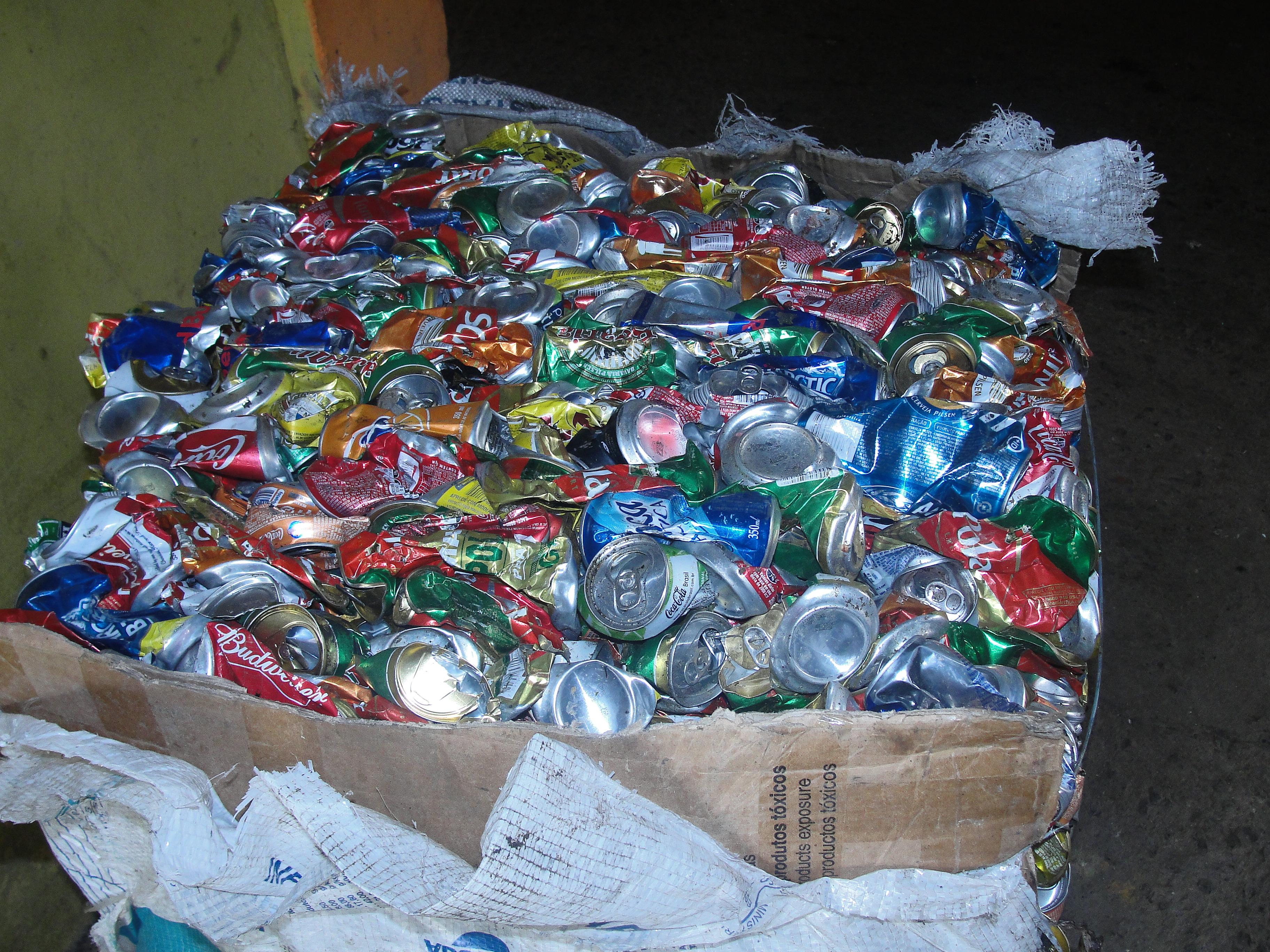 diversas latas de aluminio, de refrigerantes, sucos e bebidas alcoólicas, estão amassadas e empilhadas para o processo de reciclagem
