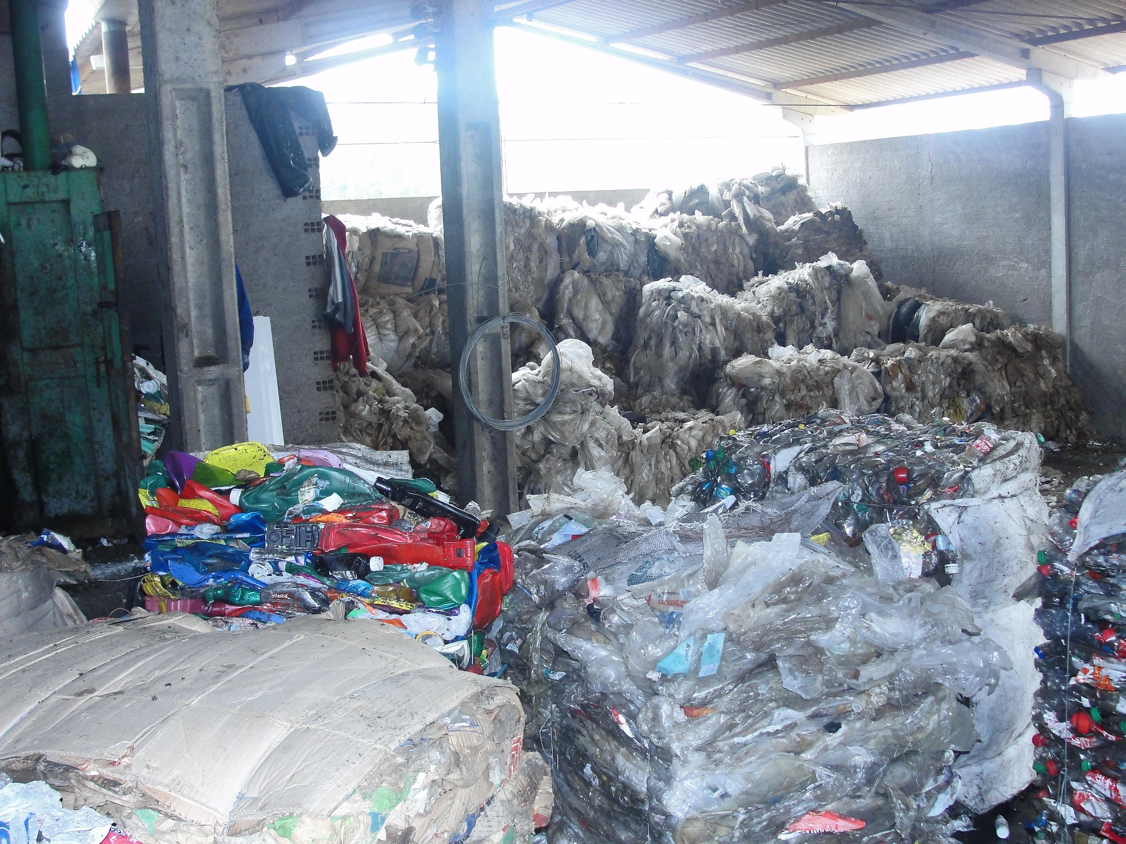 uma foto mostra os fardos de material para reciclagem, com latas de alumínio, garrafas pet e outros resíduos secos, todos organizados para processamento