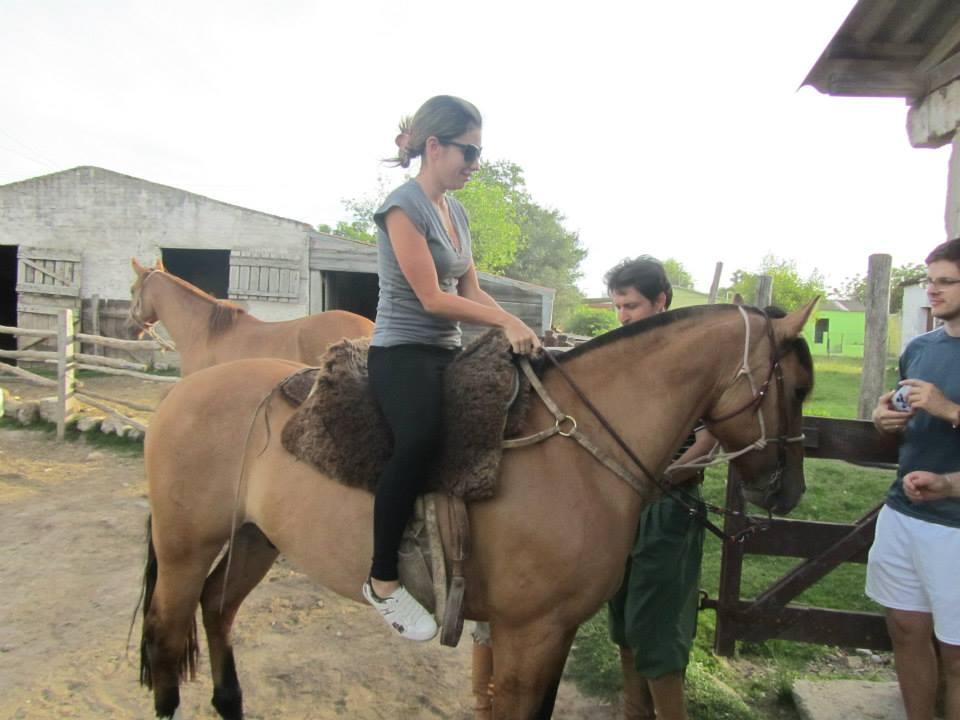 uma moça montada no cavalo é observada por dois homens, que estão a pé
