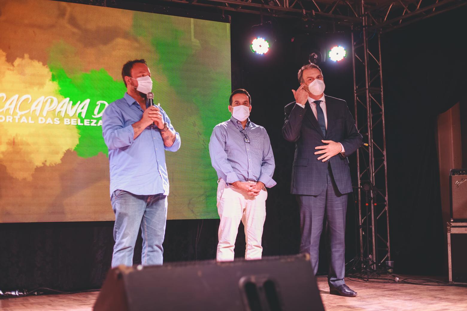 Três homens apresentam numa tela para o público o dossiê do Geoparque Caçapava.