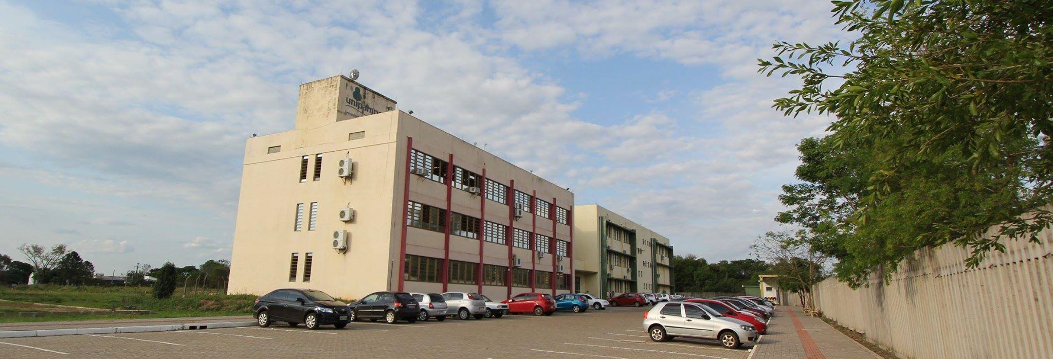 Foto mostra os dois prédios do Campus São Borja da Unipampa ao centro, com o cercado de concreto e a vegetação ornamental à direita na imagem