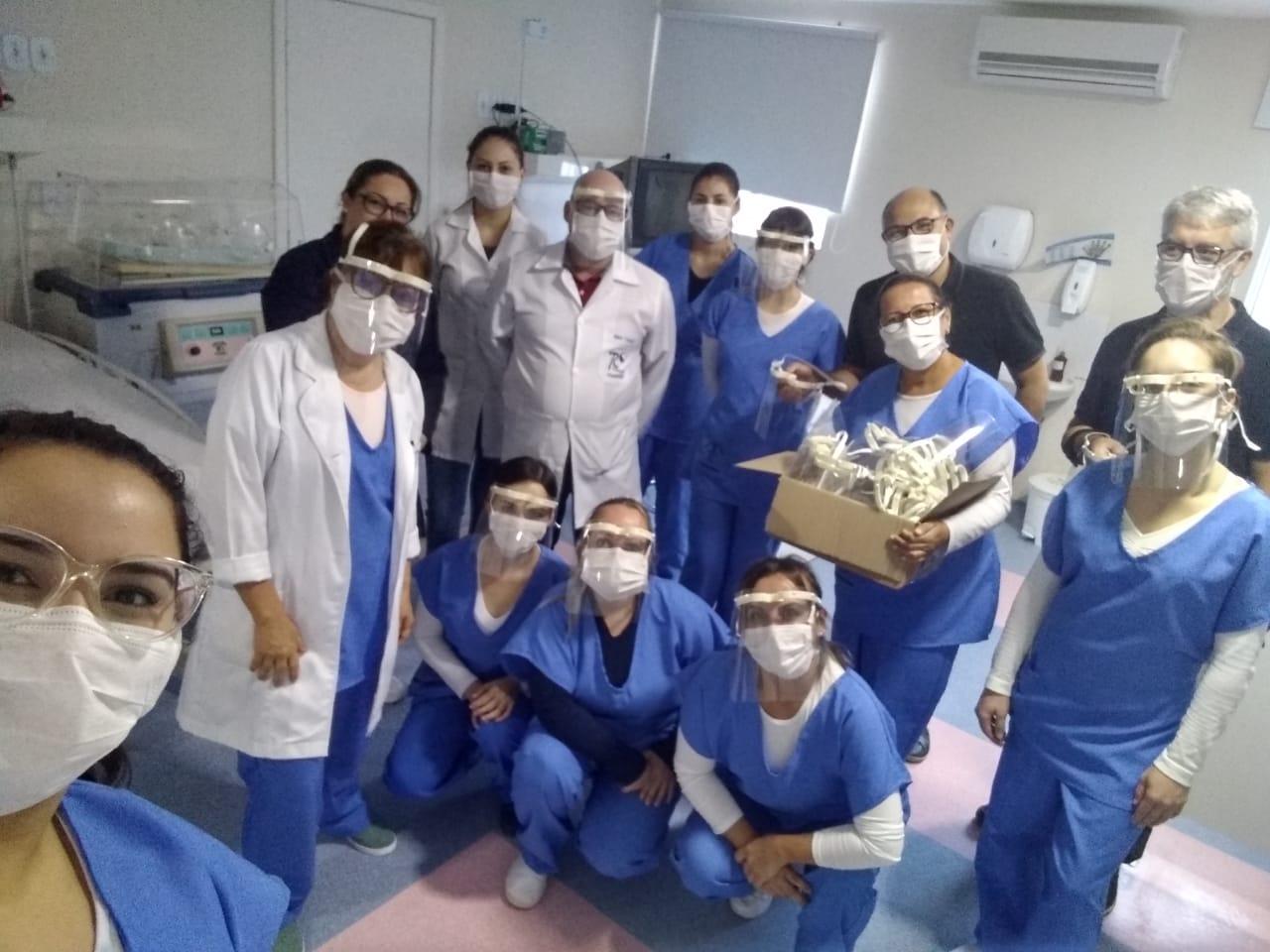 equipe médica uniformizada em hospital com os protetores faciais