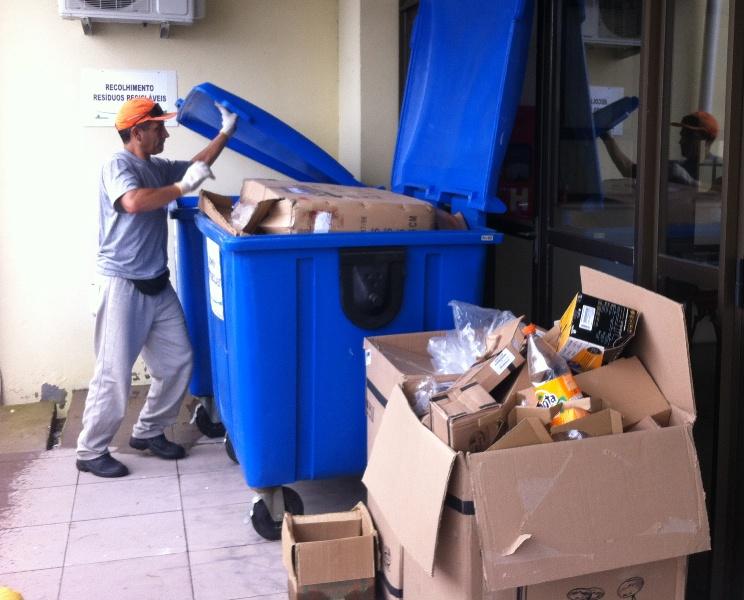 Servidor fazendo a coleta dos materiais recicláveis. Em primeiro plano caixa cheia de papelões.