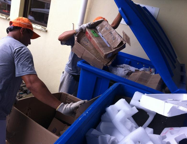 Homem coletando papelões de um lixeira. 