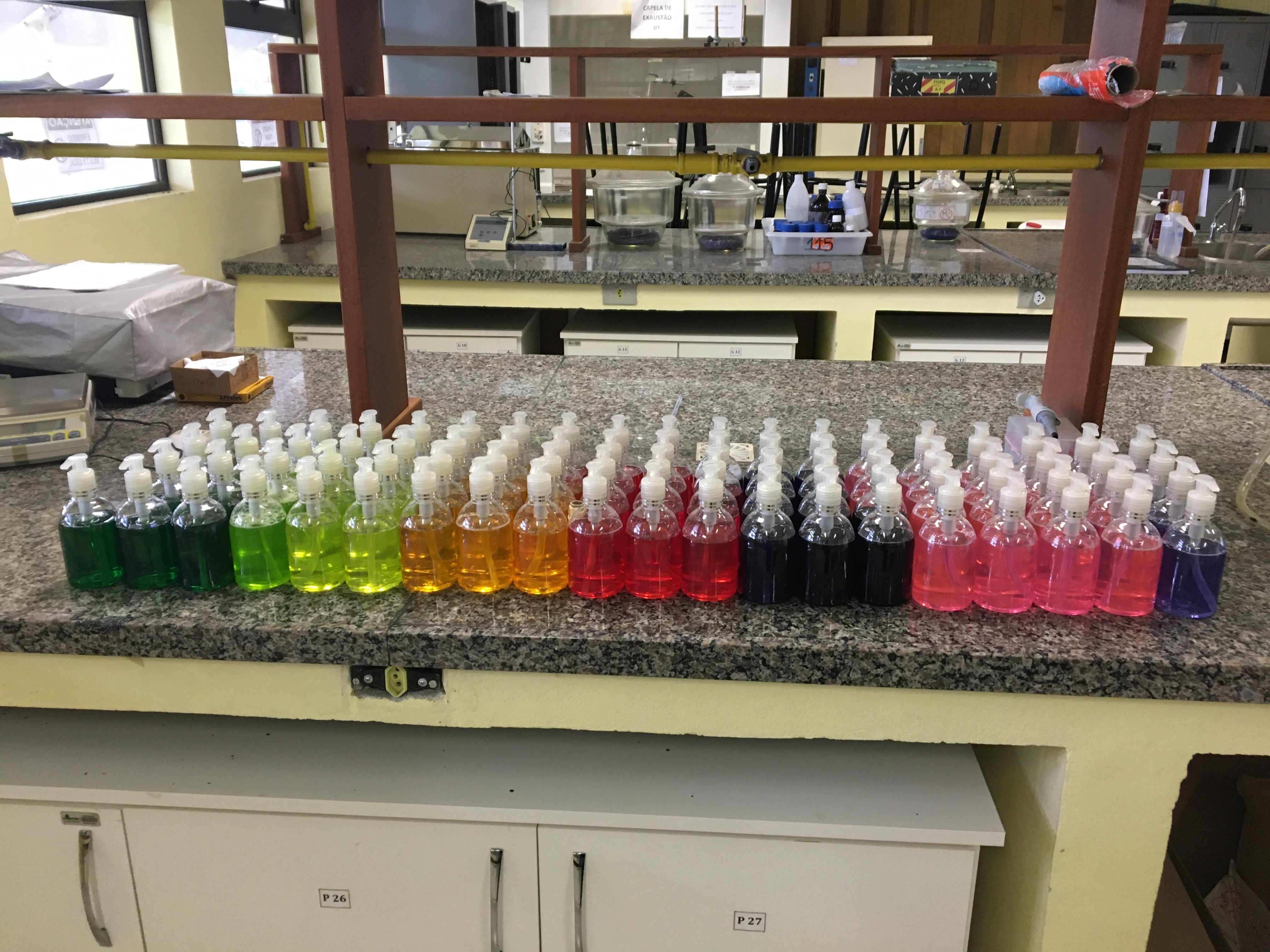 sobre uma bancada de granito em um laboratório, 73 frascos de 250ml de sabonetes em diferentes cores
