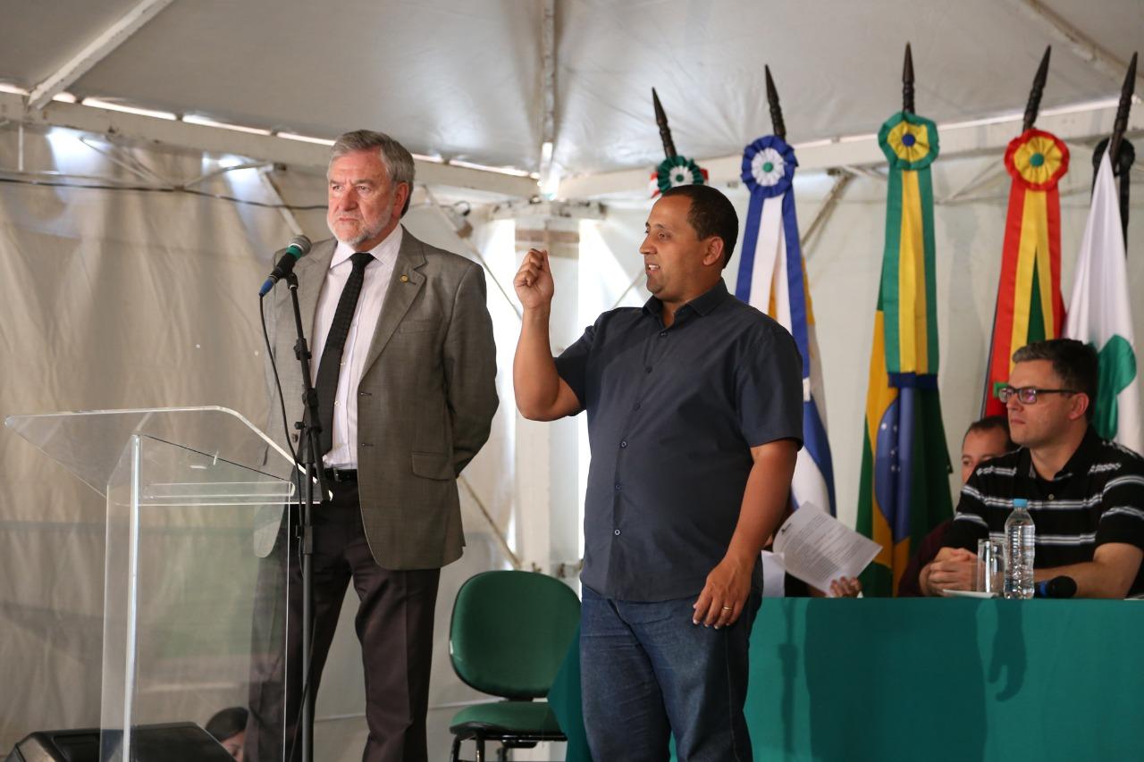 Flávio Alves Monteiro e o intérprete de libras ao lado. Bandeiras do Brasil, Rio grande do Sul, Unipampa e Mercosul ao fundo.