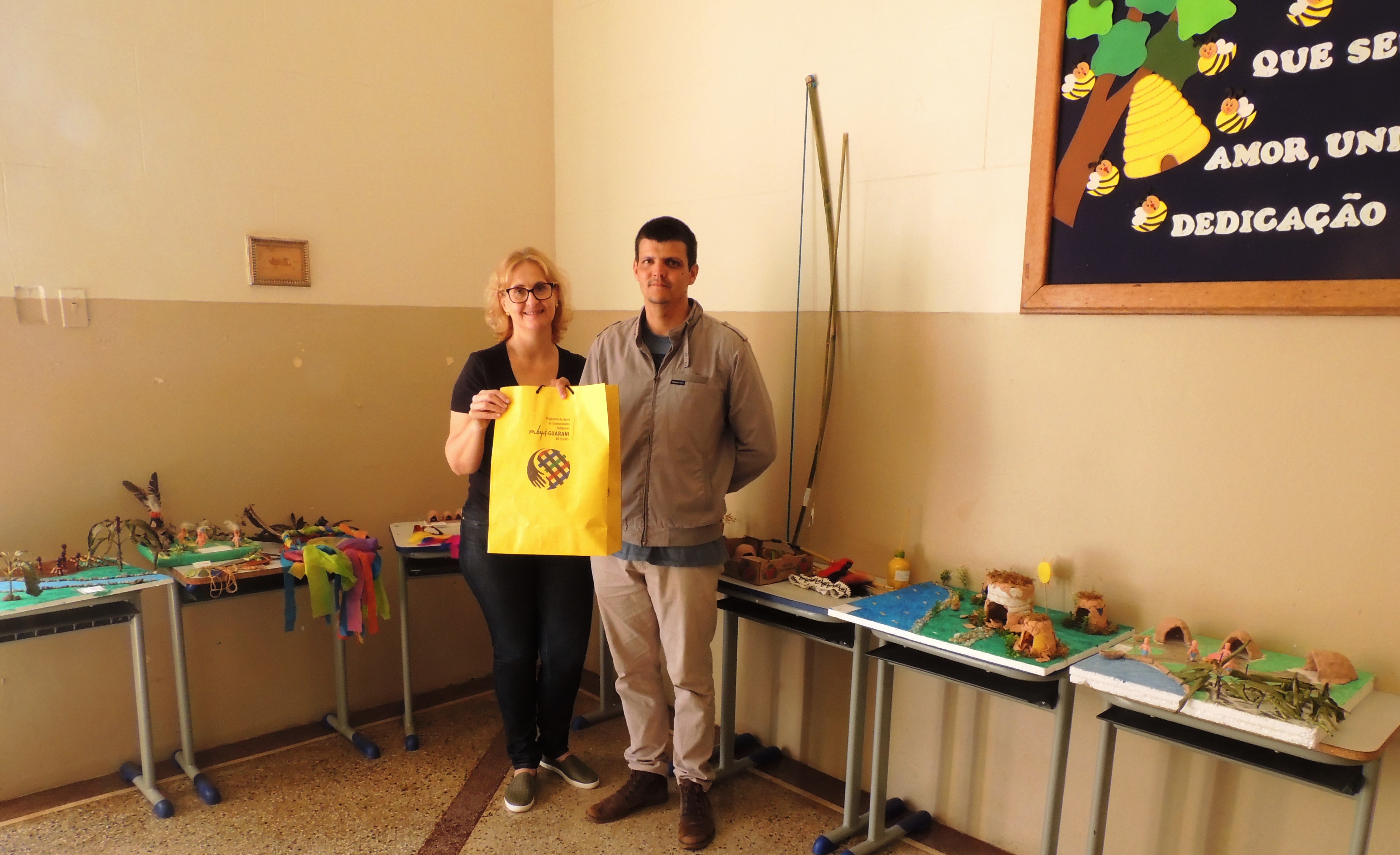 A professora Cláudia recebe do acadêmico André o kit de artesanato ao lado dos trabalhos relativos ao dia 19 de abril A professora Cláudia recebe do acadêmico André o kit de artesanato ao lado dos trabalhos relativos ao dia 19 de abril